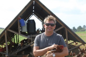 Tom Lane, founder of The Farm, with one of the 500 free-range chooks.  Photo: Candida Baker