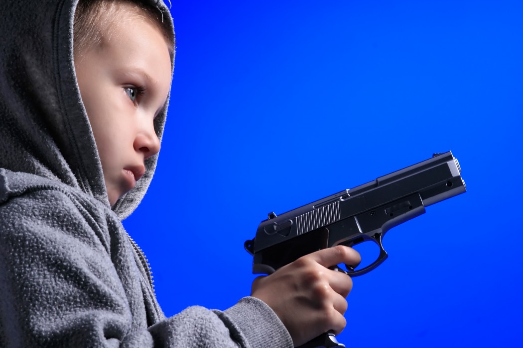a blond boy is holding a gun on blue
